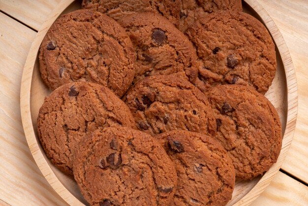 木製の背景に木製プレートのバタークッキーチョコレートチップクッキーを提供する準備ができて