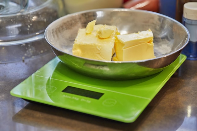 Butter in metal plate on digital scale in home kitchen