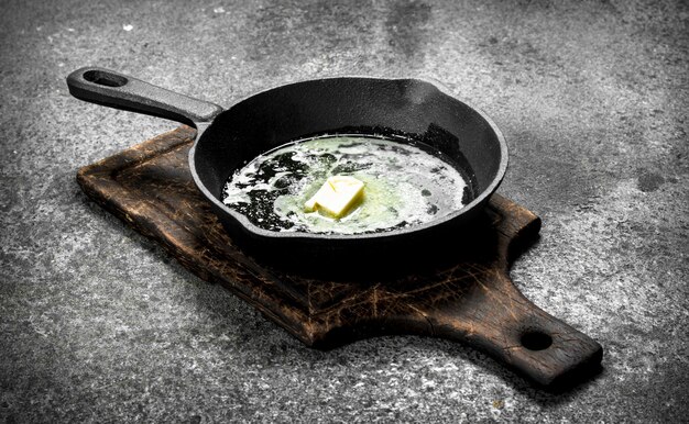 Butter in an old pan. On rustic background.