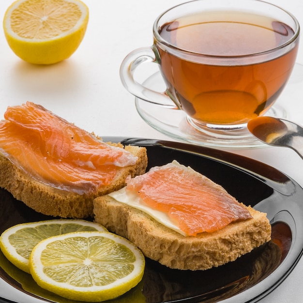 Butter sandwich, salted salmon and lemon on a black plate