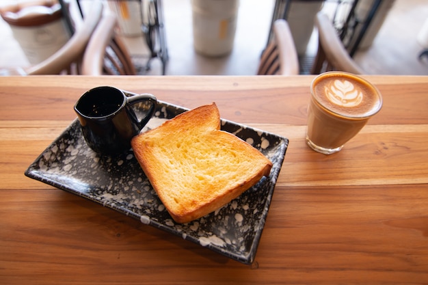 Pane tostato con zucchero e burro con miele sullo scrittorio di legno in caffetteria