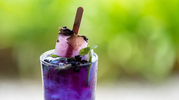 Butterfly pea Blue pea juice ijs koel drankje met limoen op houten tafel op groene bokeh achtergrond in de tuin