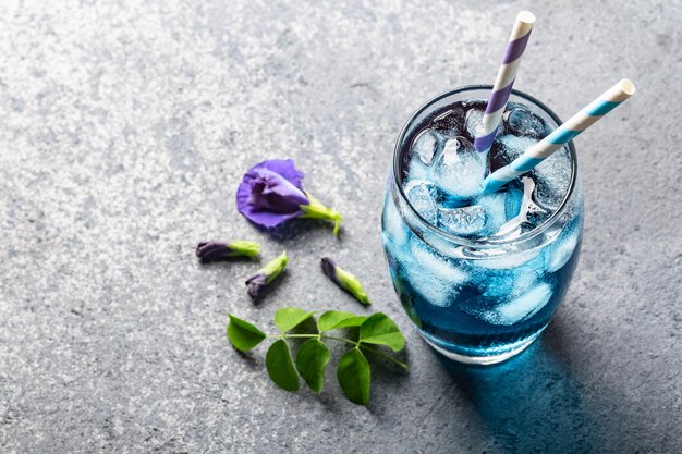 Butterfly pea flower herbal tea on grey concrete.