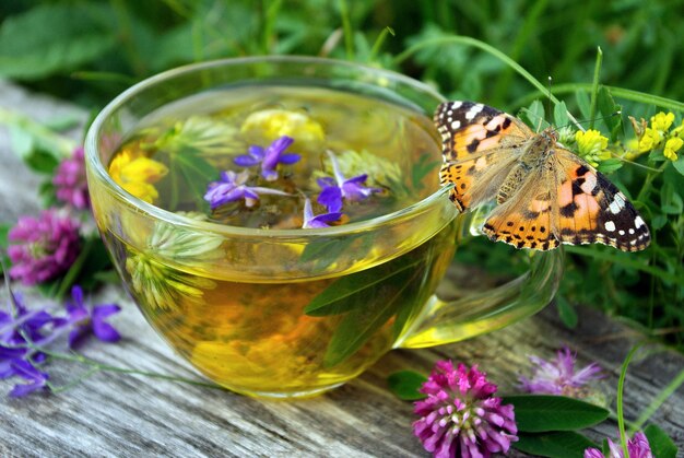 Photo a butterfly and a pitcher of tea with purple flowers and a butterfly on the side.