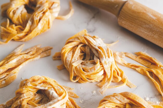 Butternut squash noodle nests and a rolling pin on marble background.