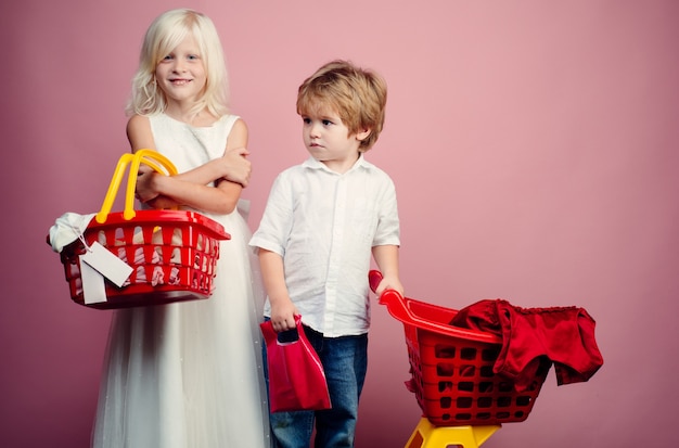 Photo buy with discount. girl and boy children shopping. couple kids hold plastic shopping basket toy. kids store. mall shopping. buy products. play shop game. cute buyer customer client hold shopping cart.