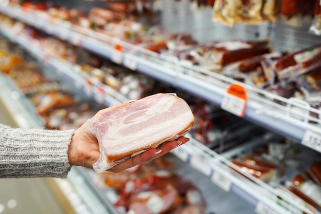 Photo buyer hand with pork meat packages at the grocery store