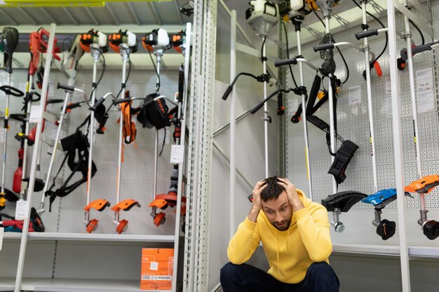 The buyer holds his hands behind his head puzzled by the high prices of garden equipment