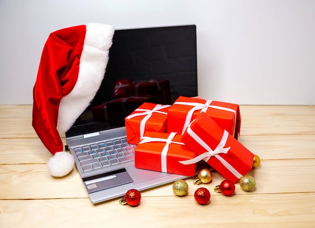 Buyer makes order on laptop, copy space on screen. woman buy presents, prepare to xmas, gift boxes and packages. purchasing things online. winter holidays sales. festive shopping with laptop