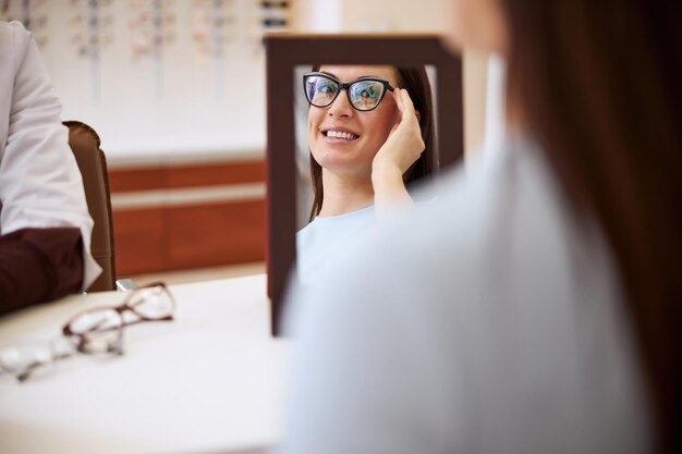 写真 提案された眼鏡をかけている彼女の反射を見ているバイヤー