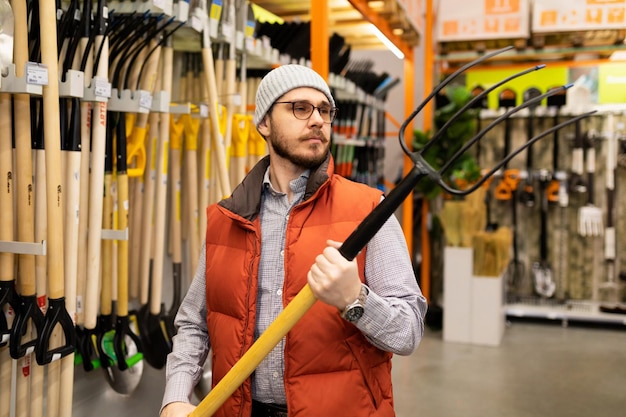 The buyer in the store chooses a new garden pitchfork