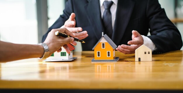 구매자는 모델 하우스를 펜으로 가리키며 부동산 중개인에게서 집을 선택합니다.