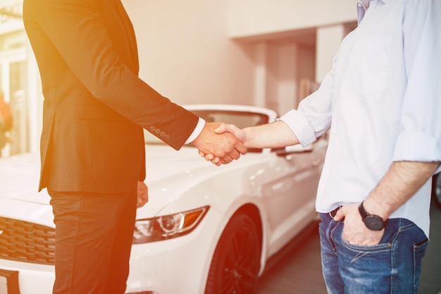 Photo buying a new car handshake and handing over the keys to the car by the salon consultant to the buyer