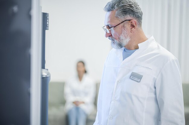 Buying a snack Grayhaired mature doctor standing near the slot machine