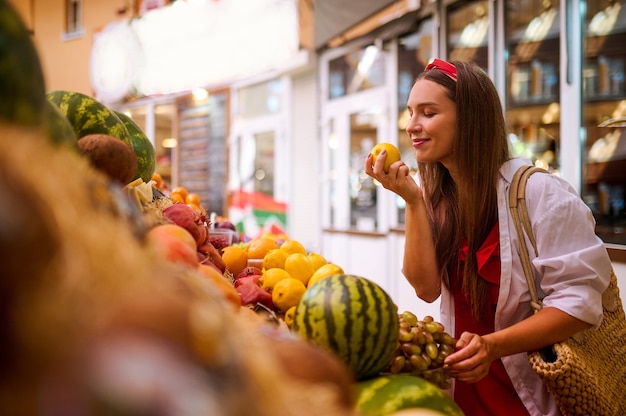 Comprare angurie. una giovane donna che sceglie un'anguria in un negozio di frutta di strada