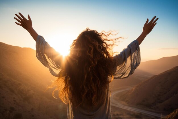 Bwoman standing with arms outstretched in front of a mountain landscape