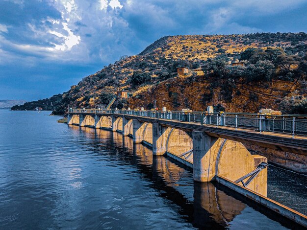 By errol ratshibvumo dam damwall water mountains trees calm