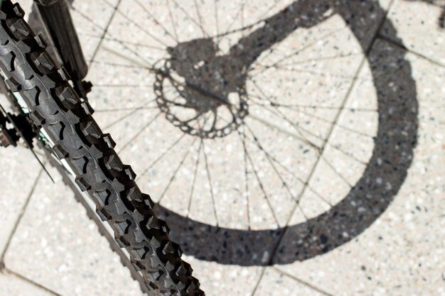 Bycycle front wheel shadow silhouette and tire view on urban concrete tile surface