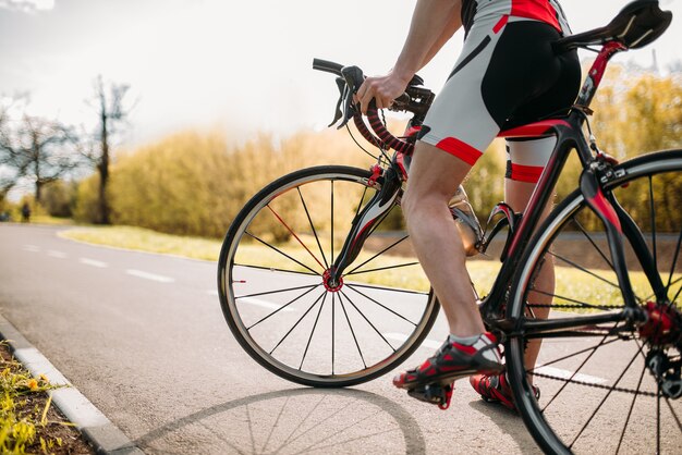 Foto ciclista in casco e abbigliamento sportivo in allenamento in bicicletta