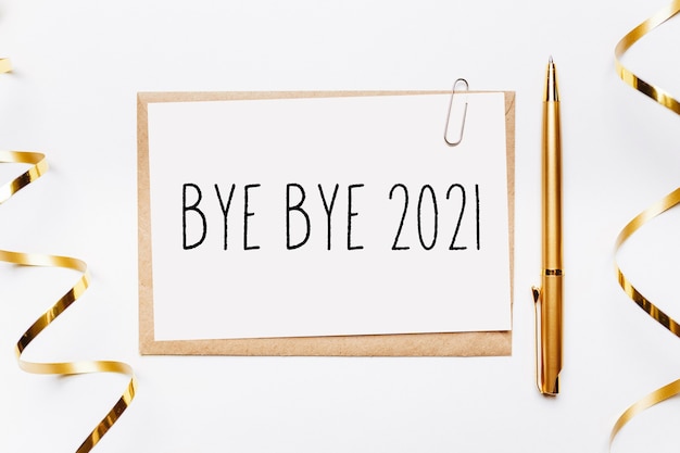 Bye bye 2021 note with envelope, gifts and gold ribbon on white background