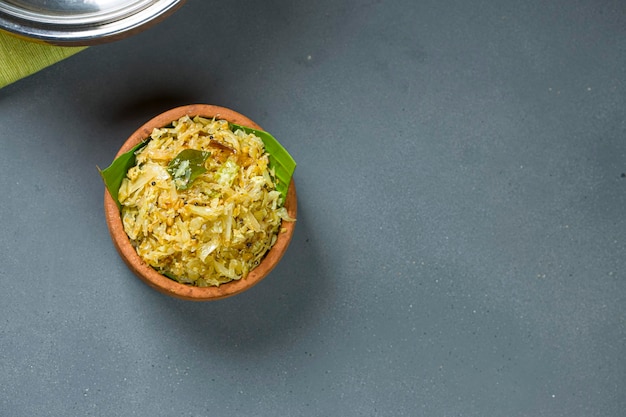 Cabbage fry or stir fryside dish for kerala meals which is  very tasty vegeterian food arranged in an earthen ware which is placed on grey textured background