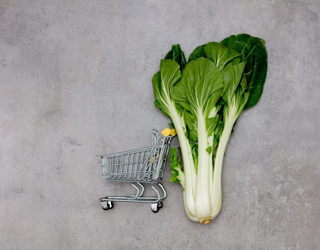 Cabbage in a little supermarket cart on a table.