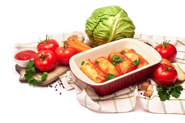 Cabbage rolls stuffed with ground beef and rice with sour cream in a baking dish and ingredients