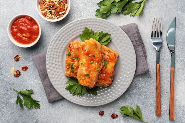 Cabbage rolls with beef, rice and vegetables on the plate. Stuffed cabbage leaves with meat. Gray concrete table