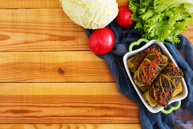 Cabbage rolls with savoy leaves on wooden background. Top view