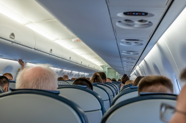 Foto nella cabina dell'aereo. passeggeri nella cabina dell'aereo. cabina di aereo commerciale con file di sedili lungo il corridoio. cabina di un aereo moderno con passeggeri sui sedili