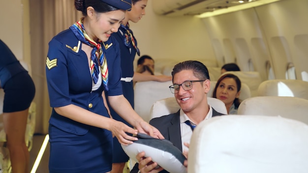 Cabin crew give service to passenger in airplane. Airline transportation and tourism concept.