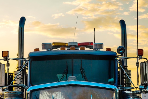 Cabine van een grote zware vrachtwagen met uitlaatpijpen tegen de achtergrond van een zonsondergang