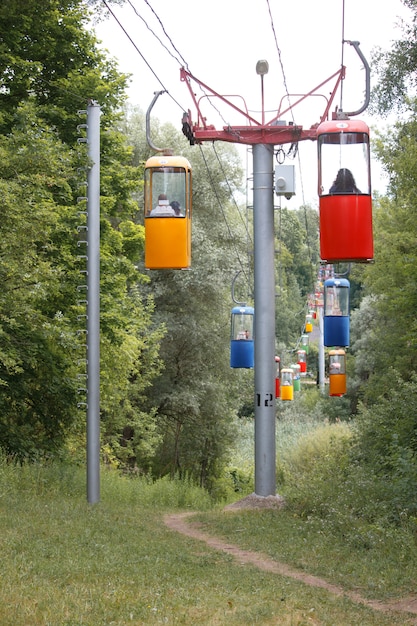 Cableway of colorful booths in the background of a dense green park