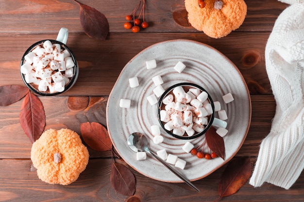 Cacao en marshmallows in mokken in herfstdecoraties met pompoenen op een houten tafel. Warme zoete dranken. Bovenaanzicht