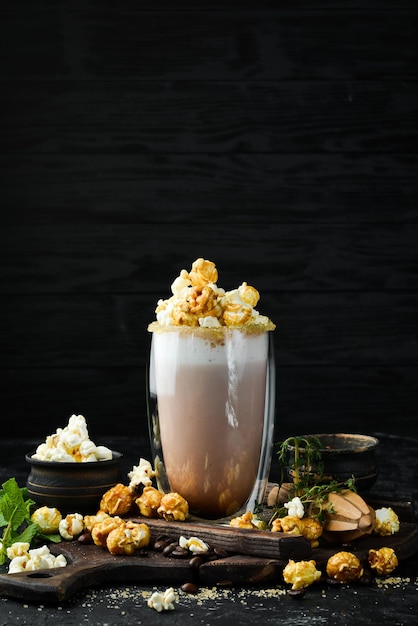 Cacao met melk en popcorn In het glas Bovenaanzicht Op een zwarte achtergrond