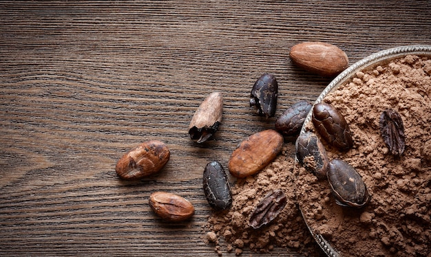 Cacao powder and cocoa beans on wooden background