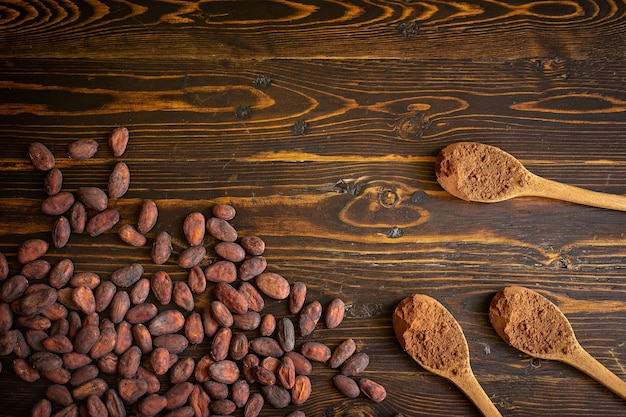 Cacaobonen en cacaopoeder in houten lepel op oude natuurlijke houten achtergrond