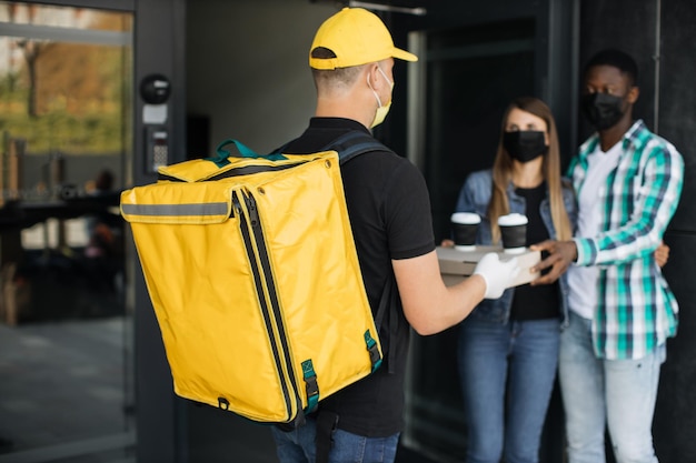 Cacasian man in face mask works on the delivery of pizza