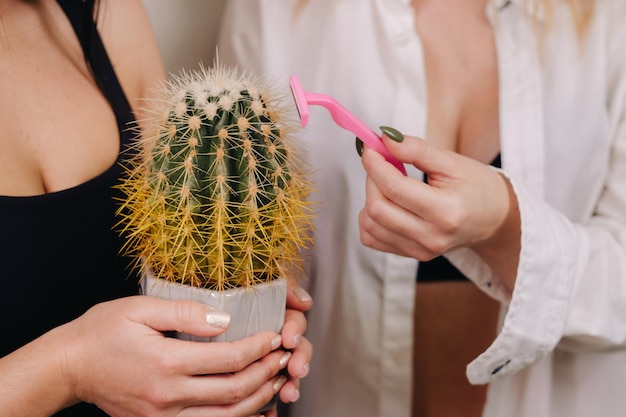 Cactusconcept Ongeschoren lichaam Eén meisje houdt een cactus in haar handen en het tweede meisje scheert een cactus Symbool van ongeschoren lichaamsdelen