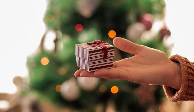 Cadeau in de hand, kerstboom bokeh achtergrond