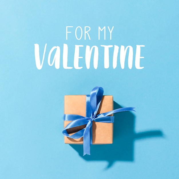 Cadeau met een blauw lint op een blauwe ondergrond, valentijnsdag concept, geliefde familie, voor hem. plat lag, bovenaanzicht
