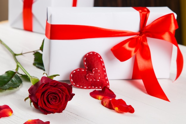 Cadeau met rood lint, rode roos en hart op wit