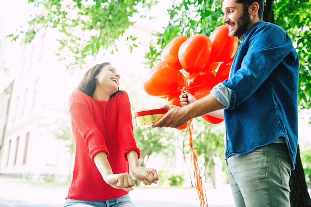 Cadeau voor geliefde vrouw. Verjaardag, Valentijnsdag en daten. Verliefd stel. Knappe man maakt verrassing voor zijn mooie schattige vriendin