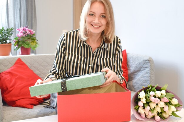 Cadeau voor vrouwen. meisje opent geschenkdoos. vreugde van verrassing. Vrouw met bloemen. Viering van de geboorte.