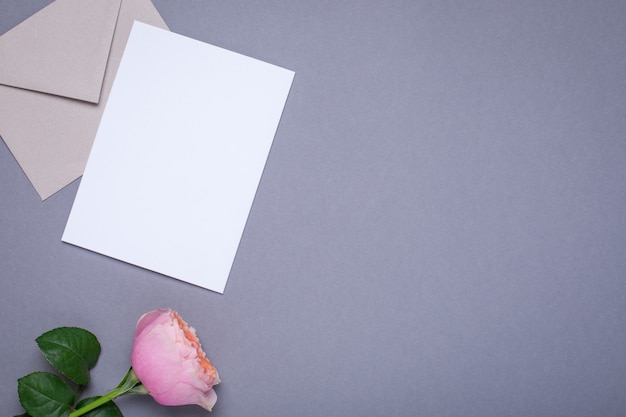 Cadeaubon en envelop met roze roos op grijs