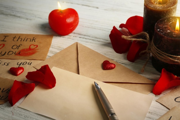 Cadeaubon voor Valentijnsdag met inscripties pen en kaarsen op witte houten achtergrond