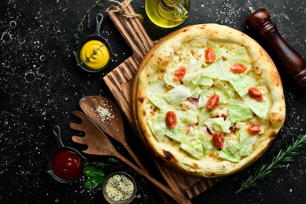 Caesar pizza with chicken classic pizza On a black stone background Top view