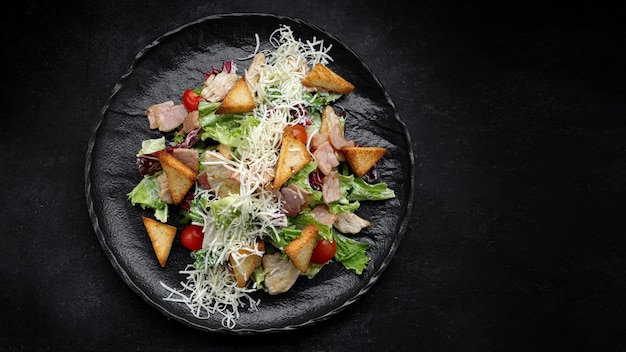 Caesar salad on a black plate Horizontal