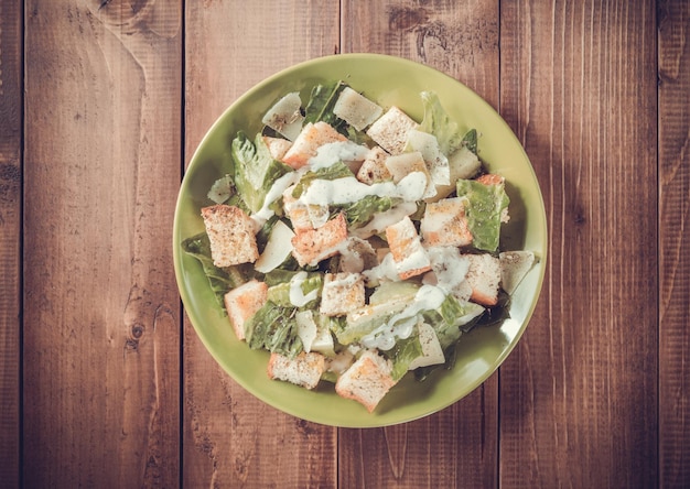 Foto insalata caesar in piatto su fondo in legno