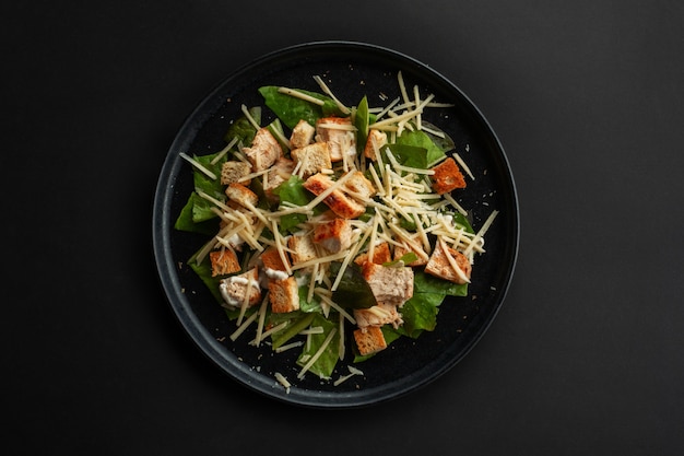 Caesar salad top view on black table over black table background